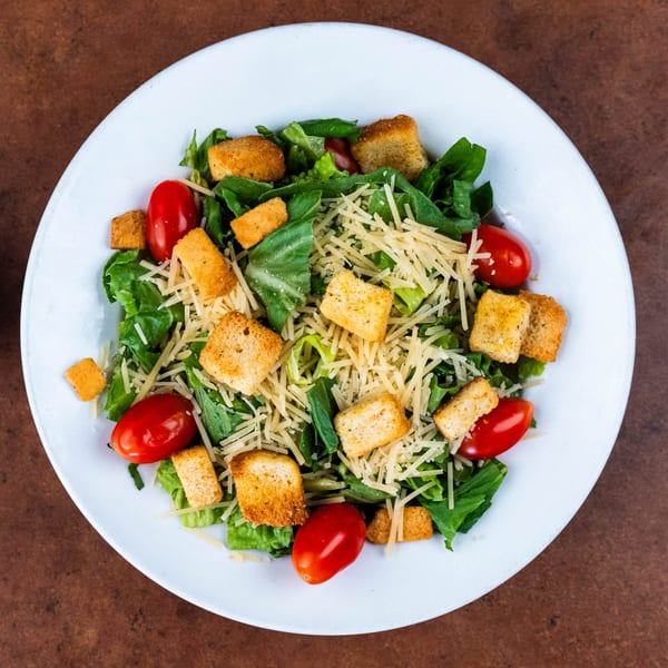 A Caesar salad with romaine lettuce, cherry tomatoes, croutons, and shredded Parmesan cheese.