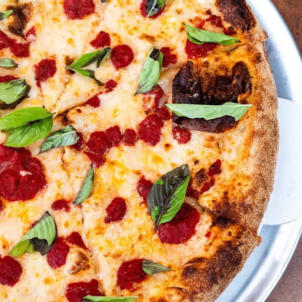 Close-up of a Pizza Buzz Margherita pizza with fresh basil leaves and rich tomato sauce.