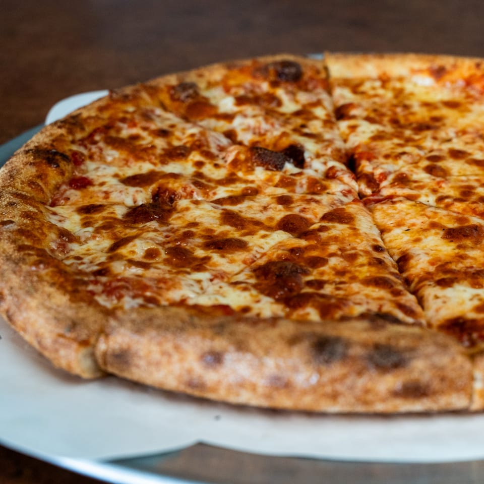 A freshly baked Pizza Buzz cheese pizza with a golden crust, sliced and ready to eat.